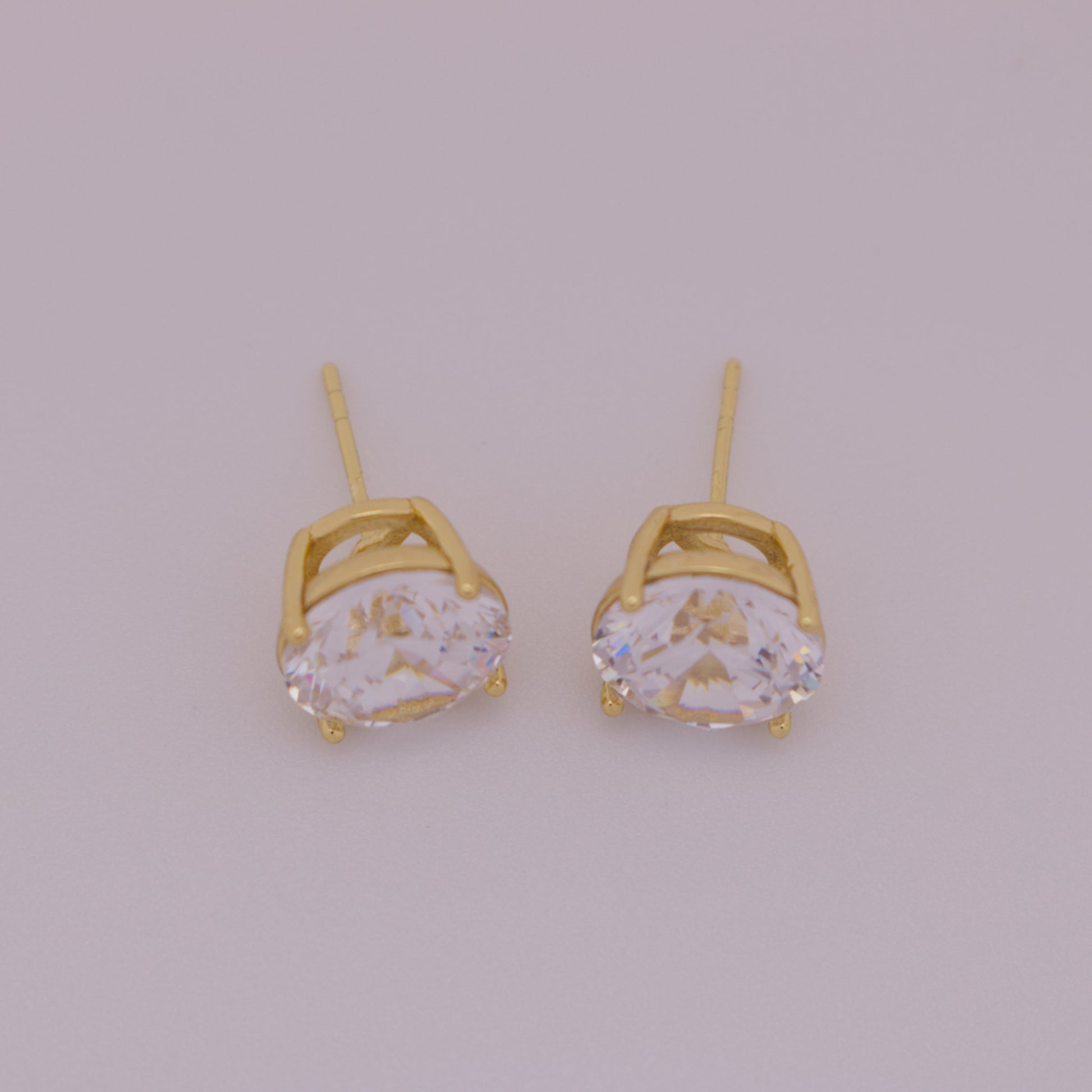 Gold earrings with clear gemstones on a light gray background