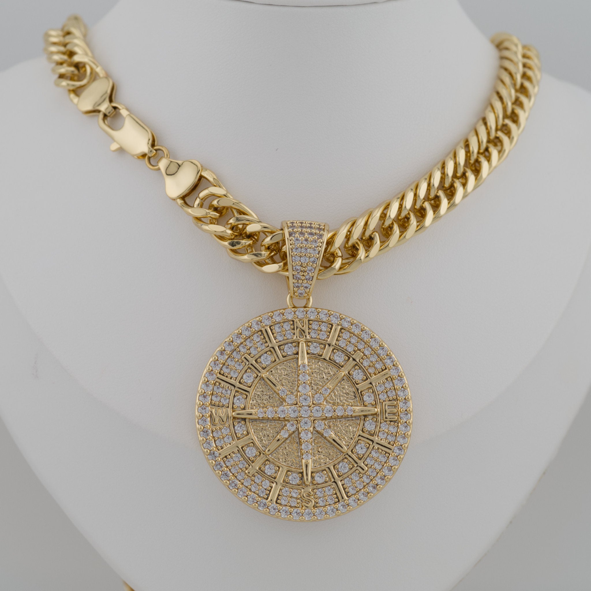 Gold necklace with a large, intricate pendant on a mannequin.