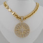 Gold necklace with a large, intricate pendant on a mannequin.