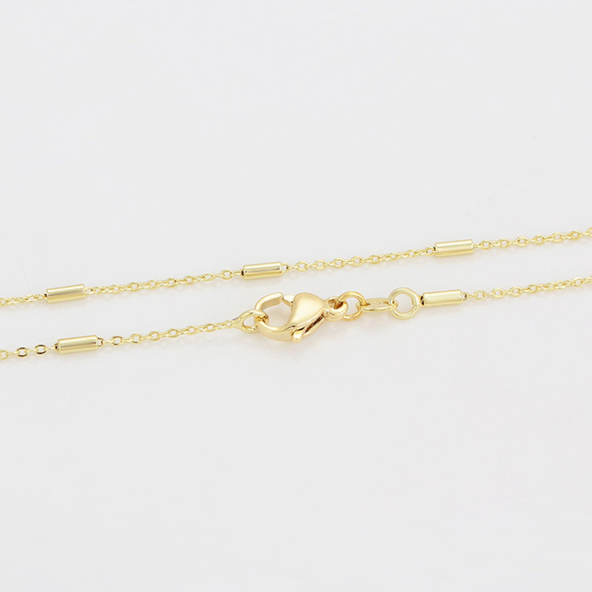 Gold chain necklace with a clasp on a light gray background