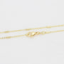 Gold chain necklace with a clasp on a light gray background
