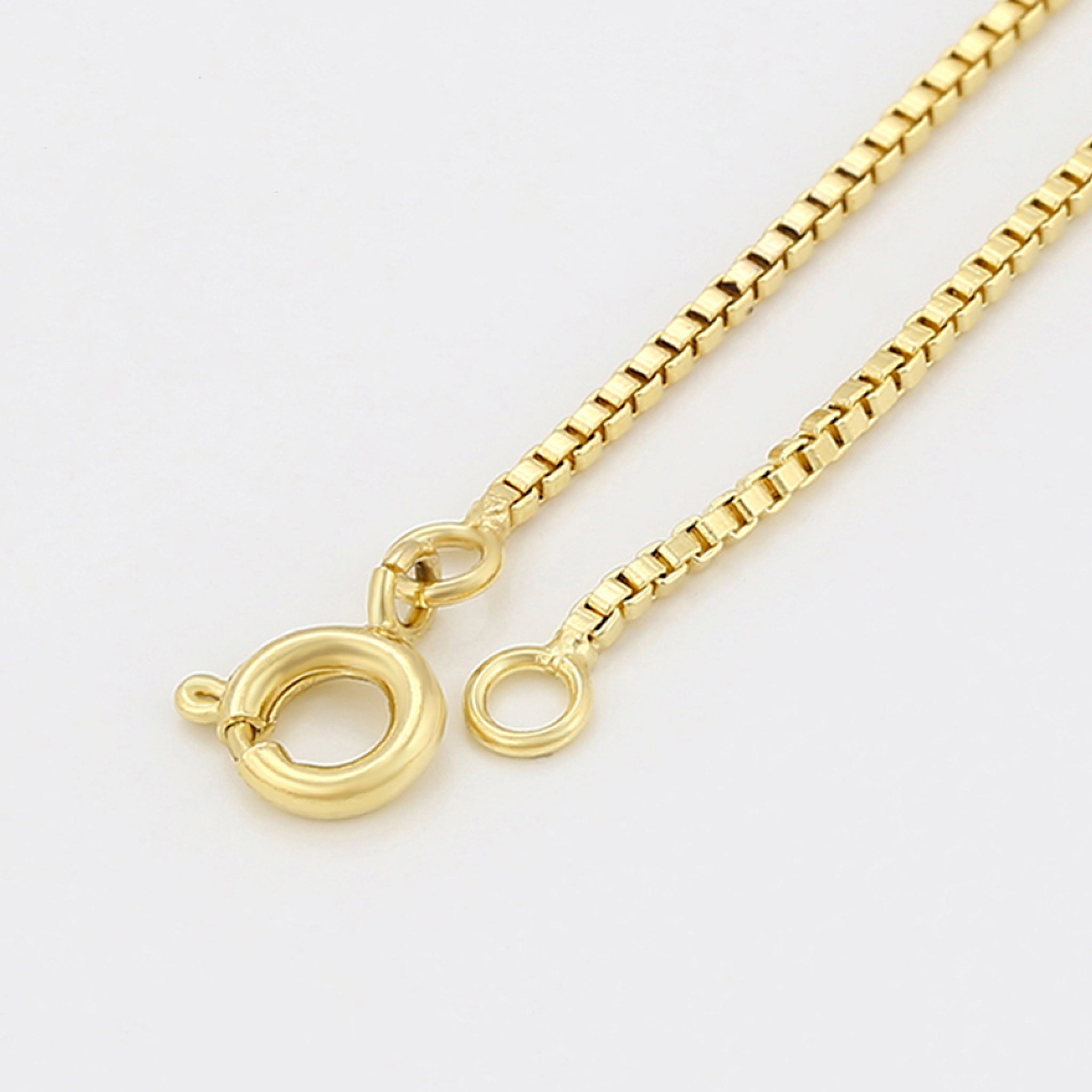 Gold chain necklace with a clasp on a light gray background