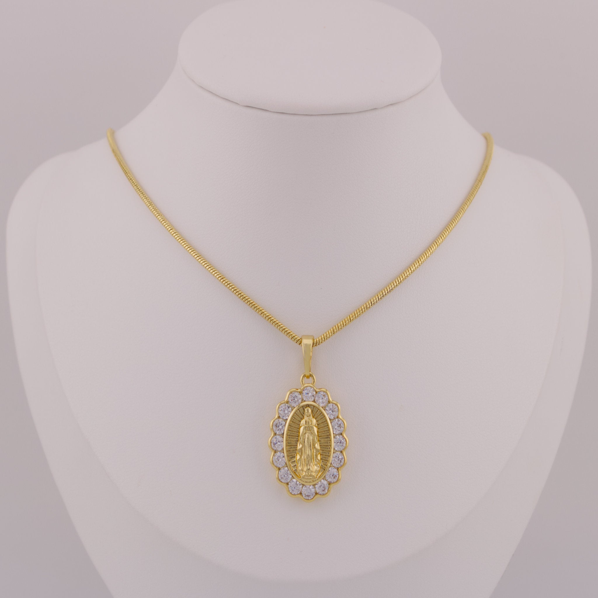 Gold necklace with a pendant on a mannequin bust against a gray background