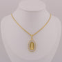 Gold necklace with a pendant on a mannequin bust against a gray background