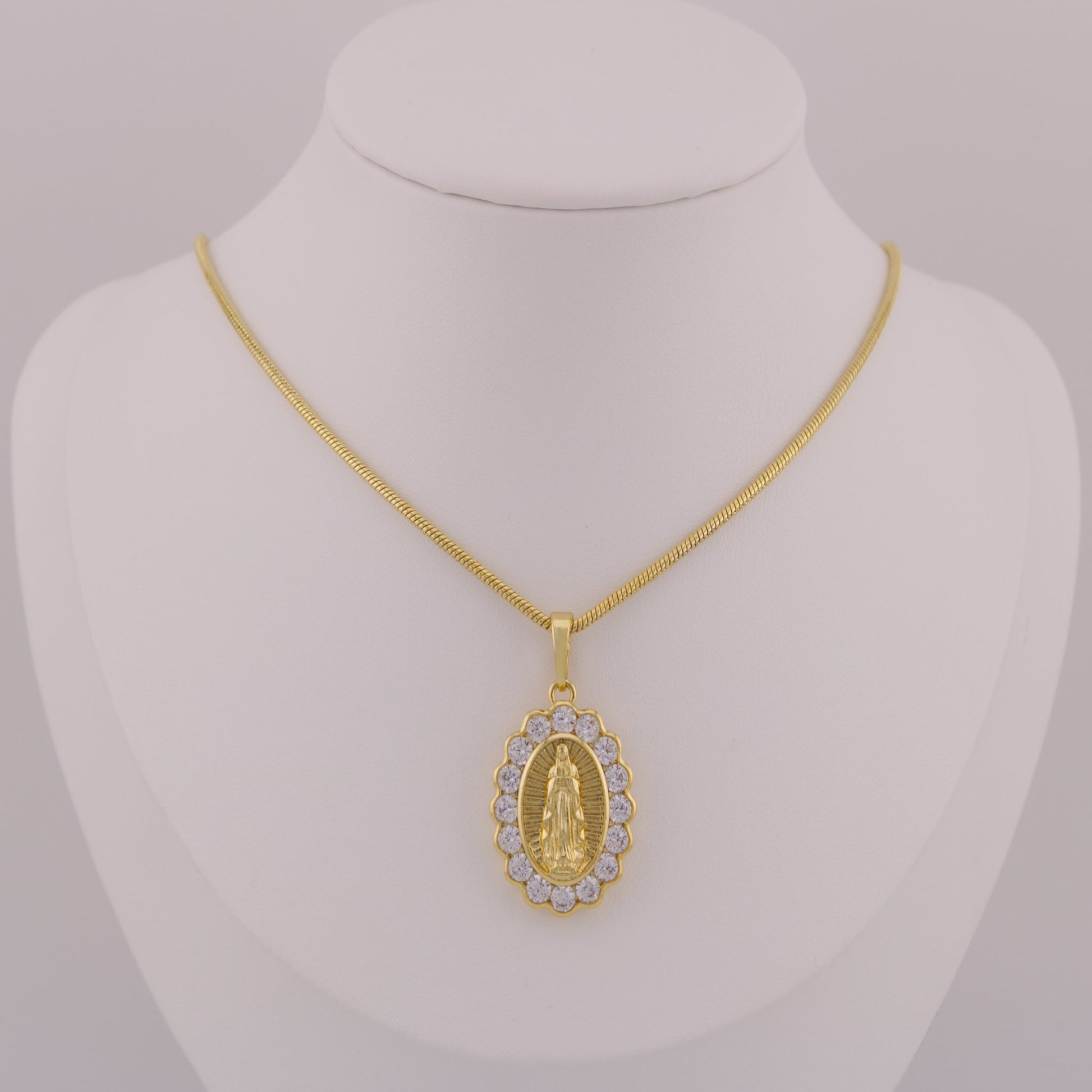 Gold necklace with a pendant on a mannequin bust against a gray background