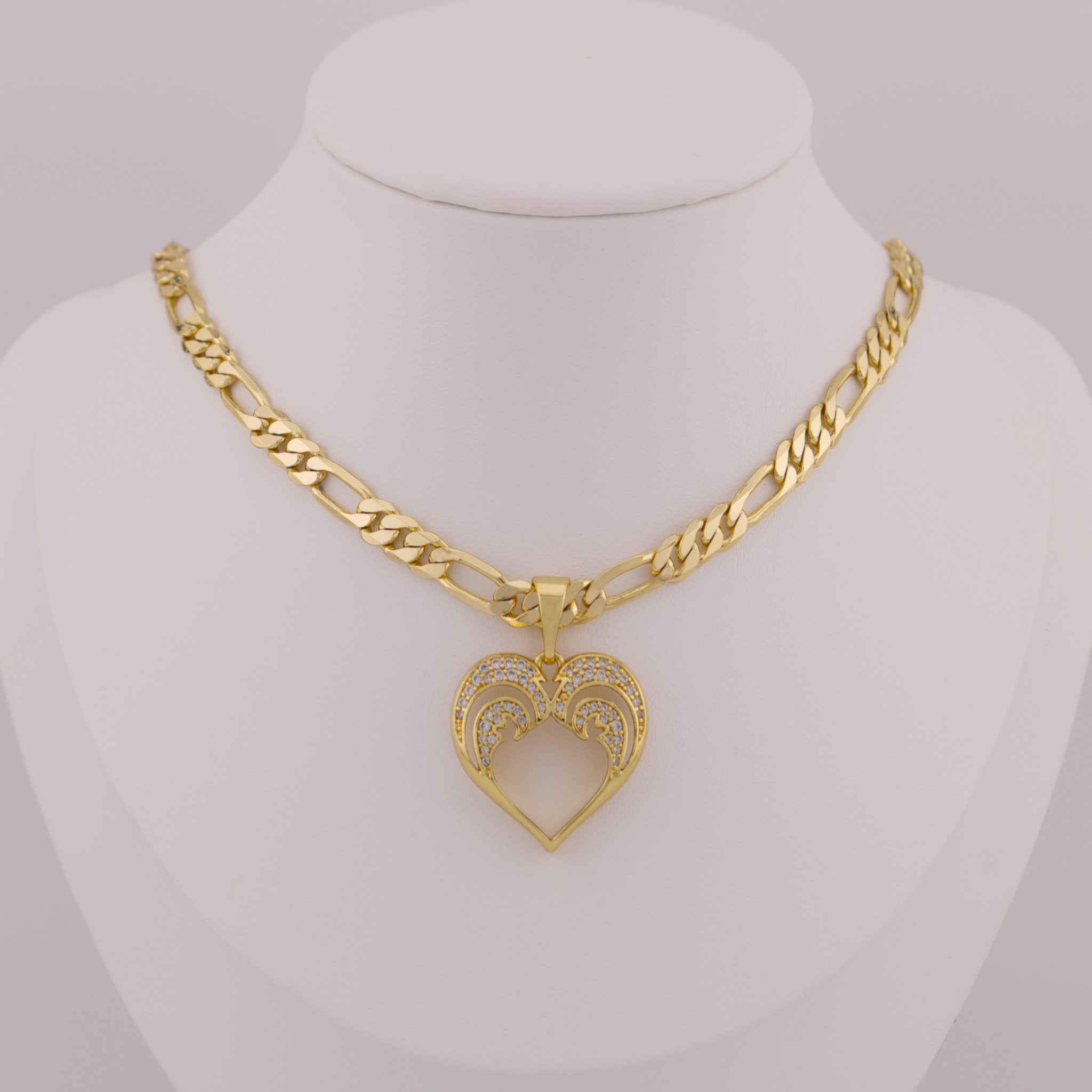 Gold necklace with a heart-shaped pendant on a mannequin bust.