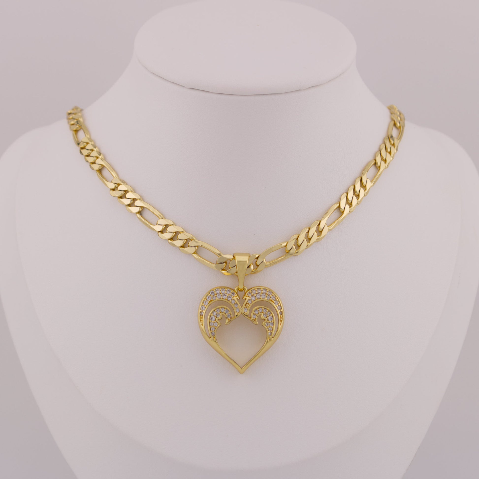 Gold necklace with a heart-shaped pendant on a mannequin bust.