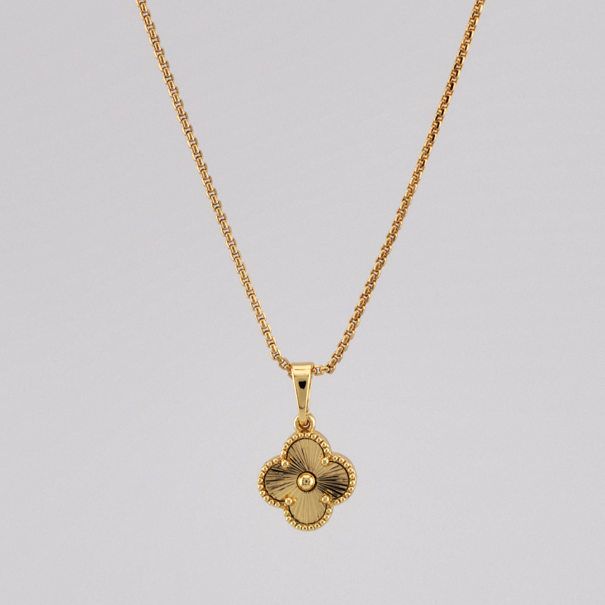Gold necklace with a pendant on a gray background