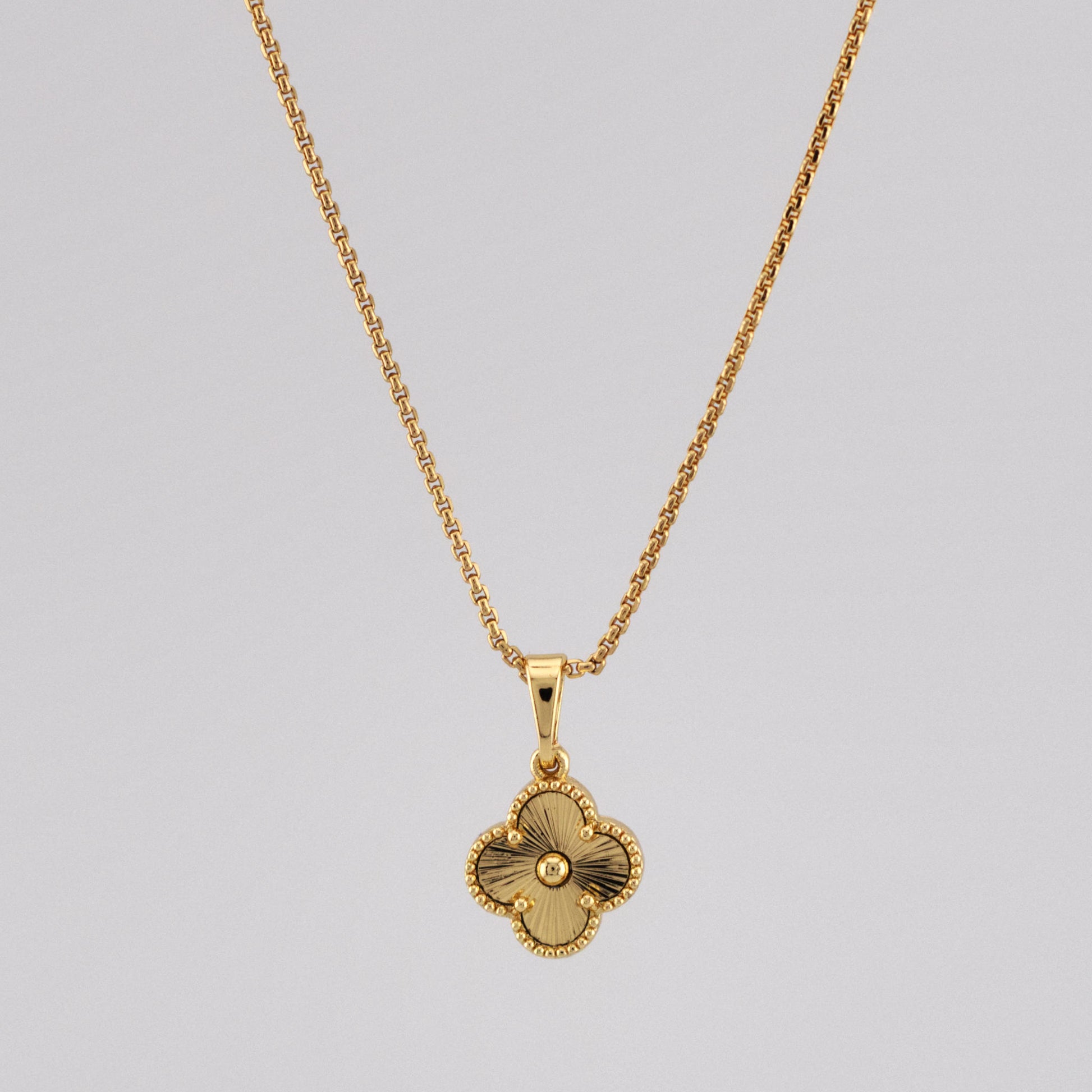 Gold necklace with a pendant on a gray background