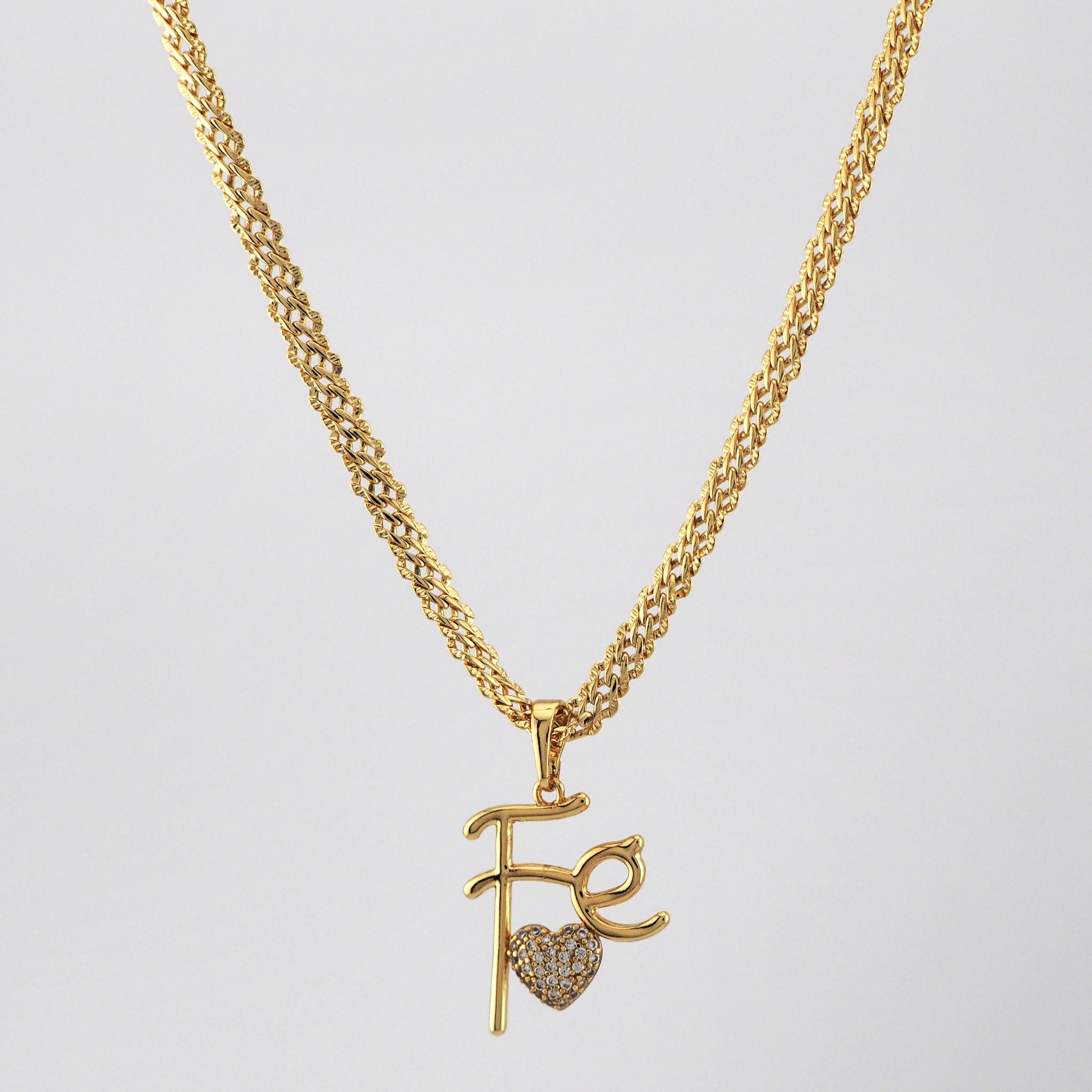 Gold necklace with pendant on a light gray background