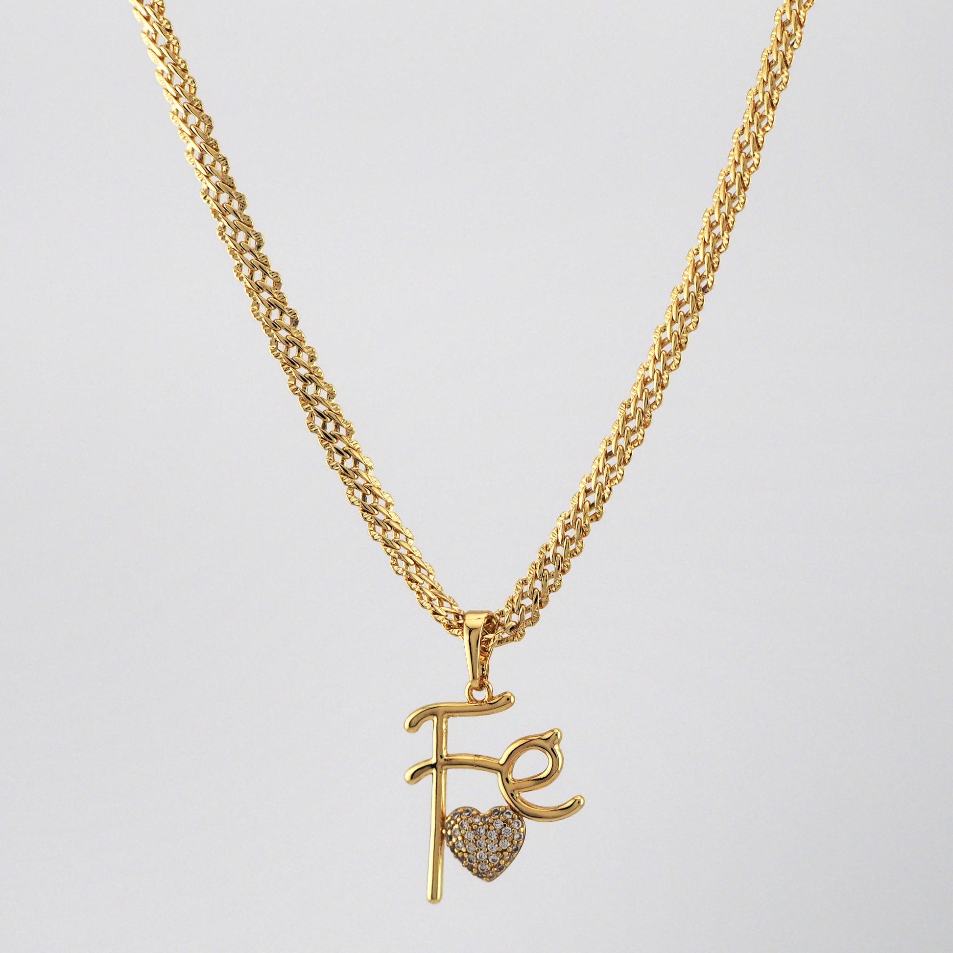 Gold necklace with pendant on a light gray background
