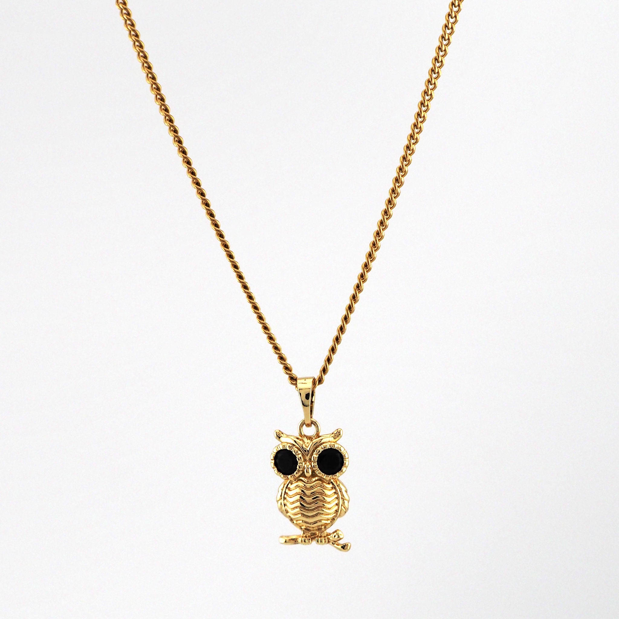 Gold owl pendant necklace on a white background