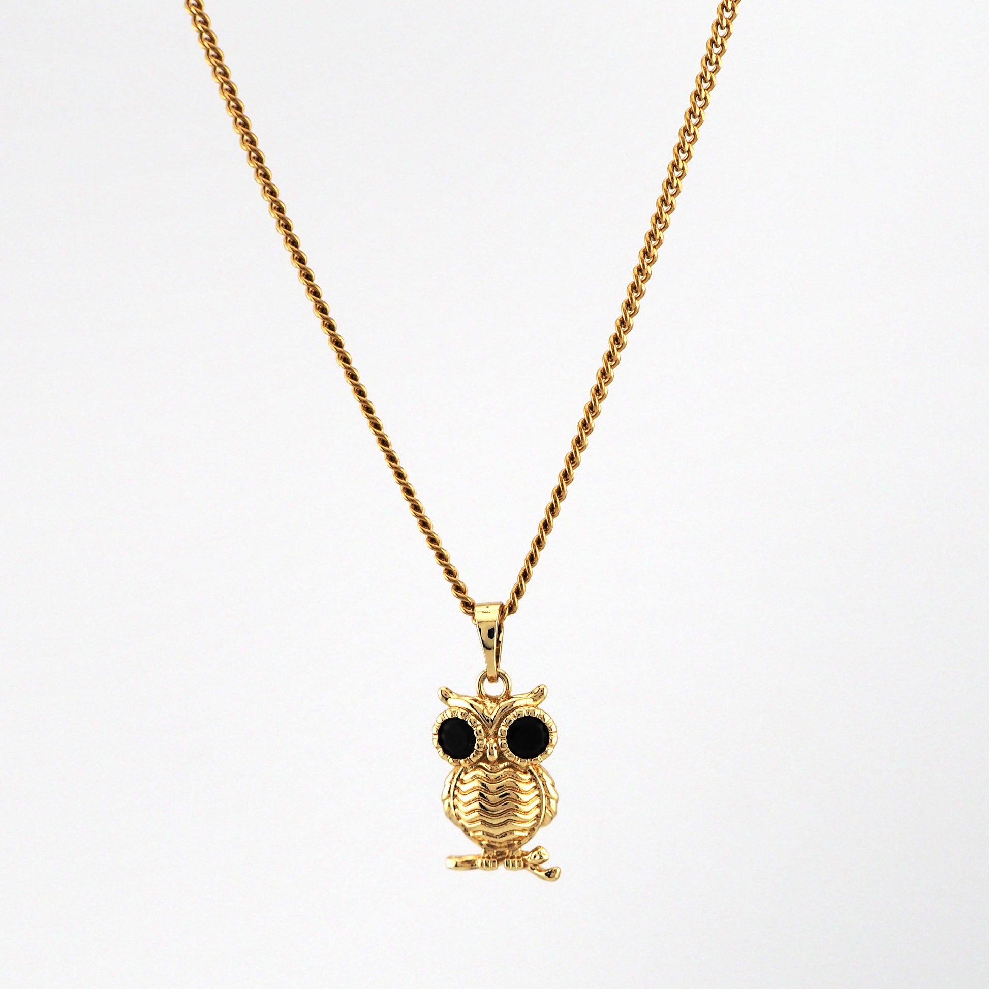Gold owl pendant necklace on a white background