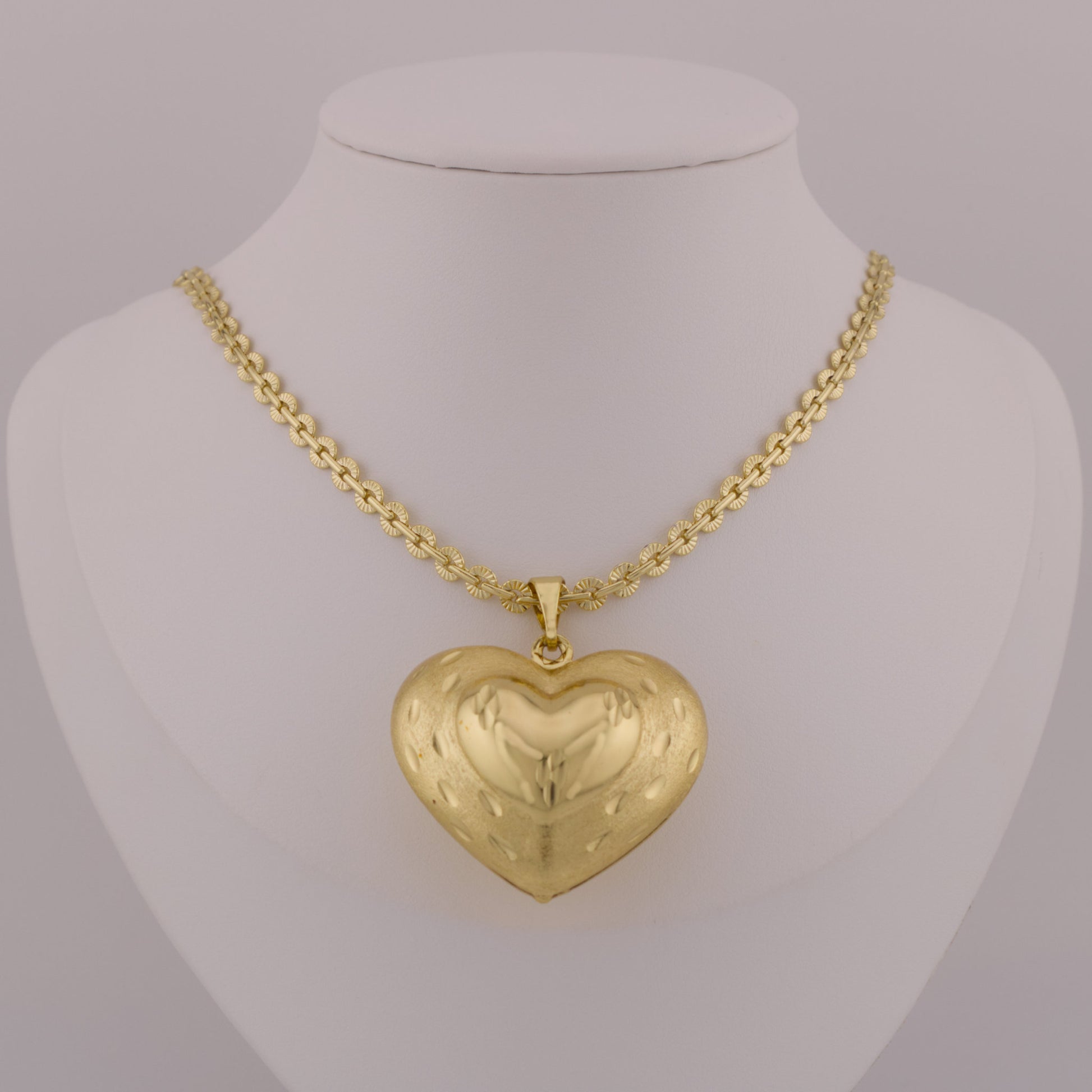 Gold heart-shaped pendant on a mannequin neck with a gray background