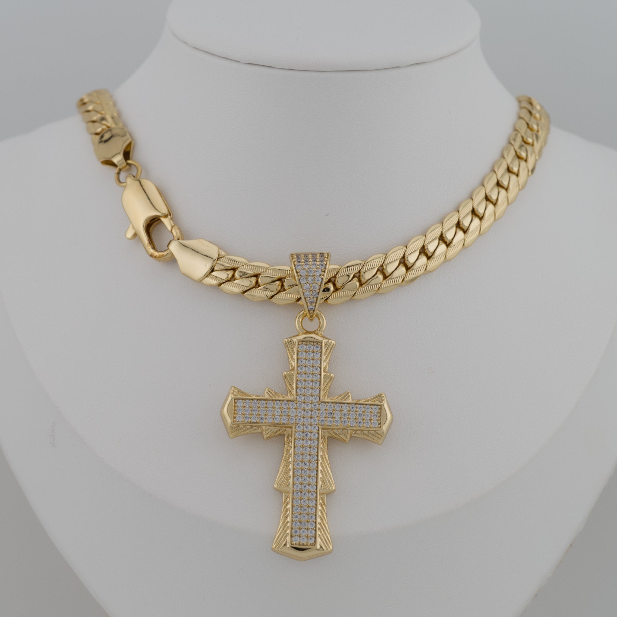 Gold chain necklace with a cross pendant on a mannequin.