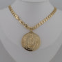 Gold chain necklace with a pendant on Virgen de Guadalupe against a gray background