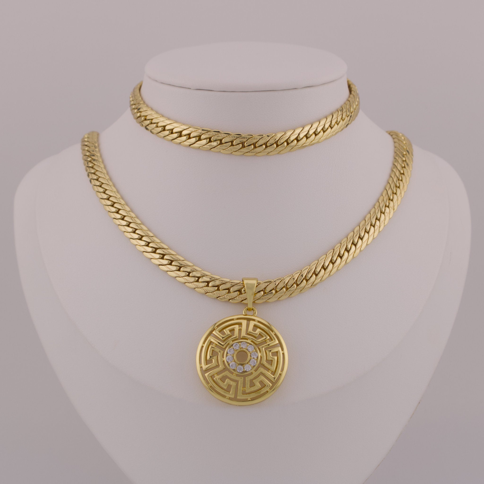 Gold chain necklace with a medallion pendant on a mannequin bust.