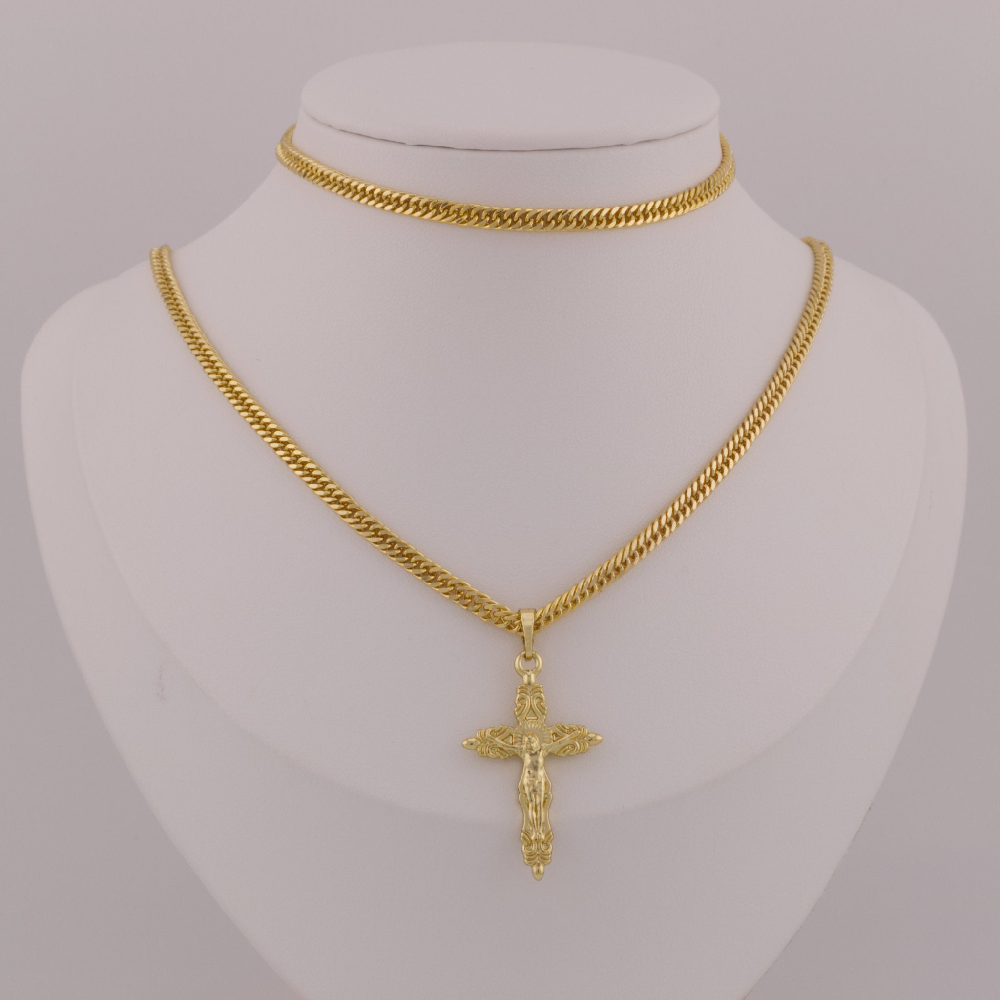 Gold chain necklace with a cross pendant on a mannequin bust.