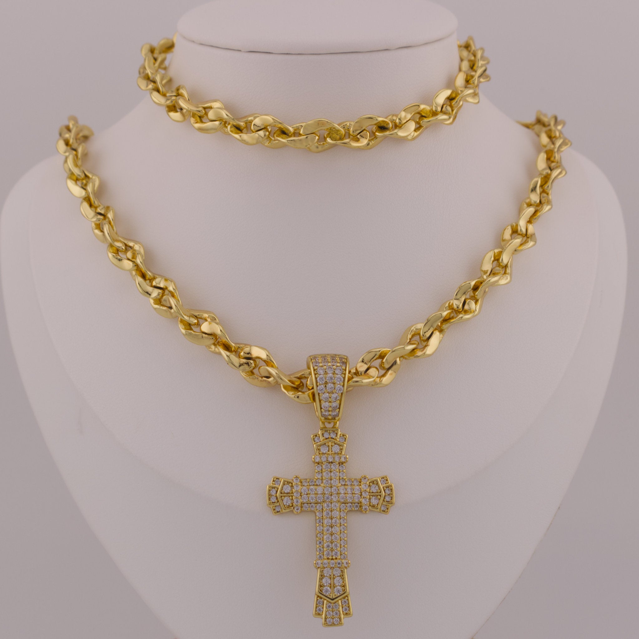Gold chain necklace with a cross pendant on a mannequin bust.