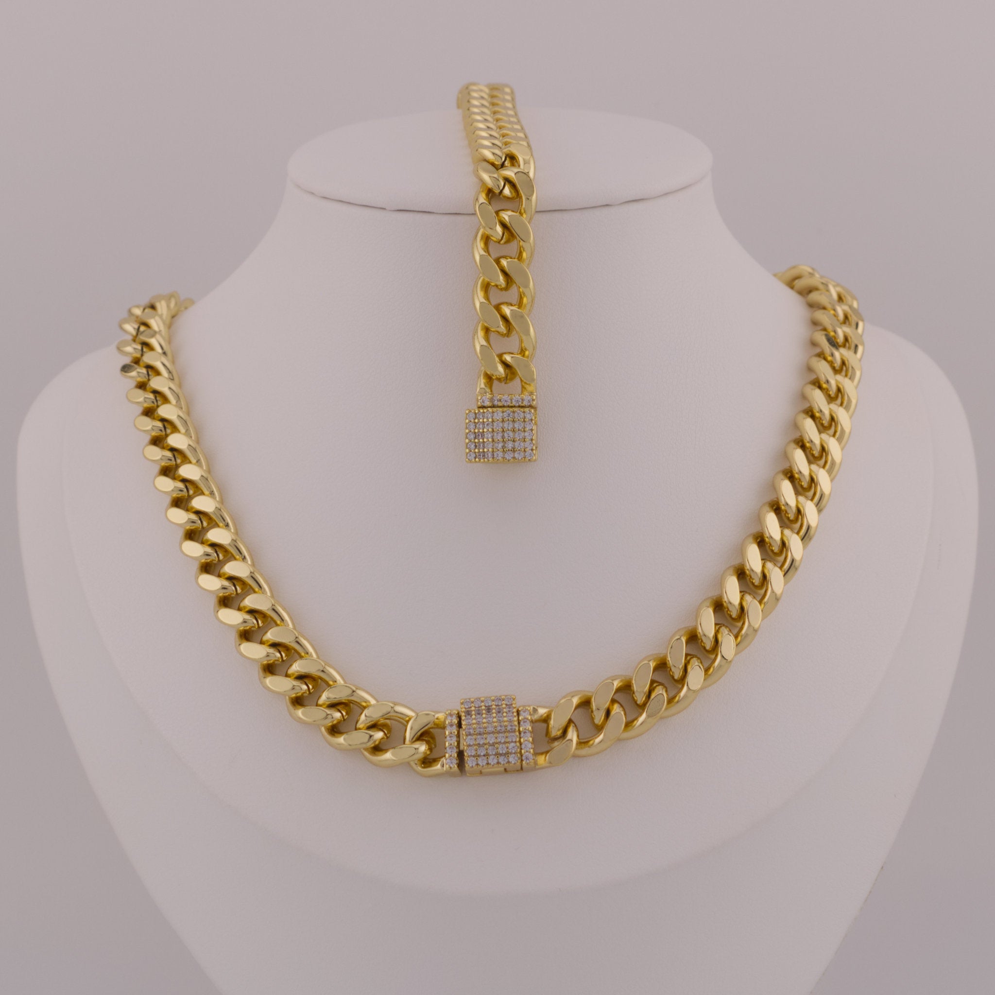 Gold chain necklace and bracelet set on a mannequin bust against a gray background