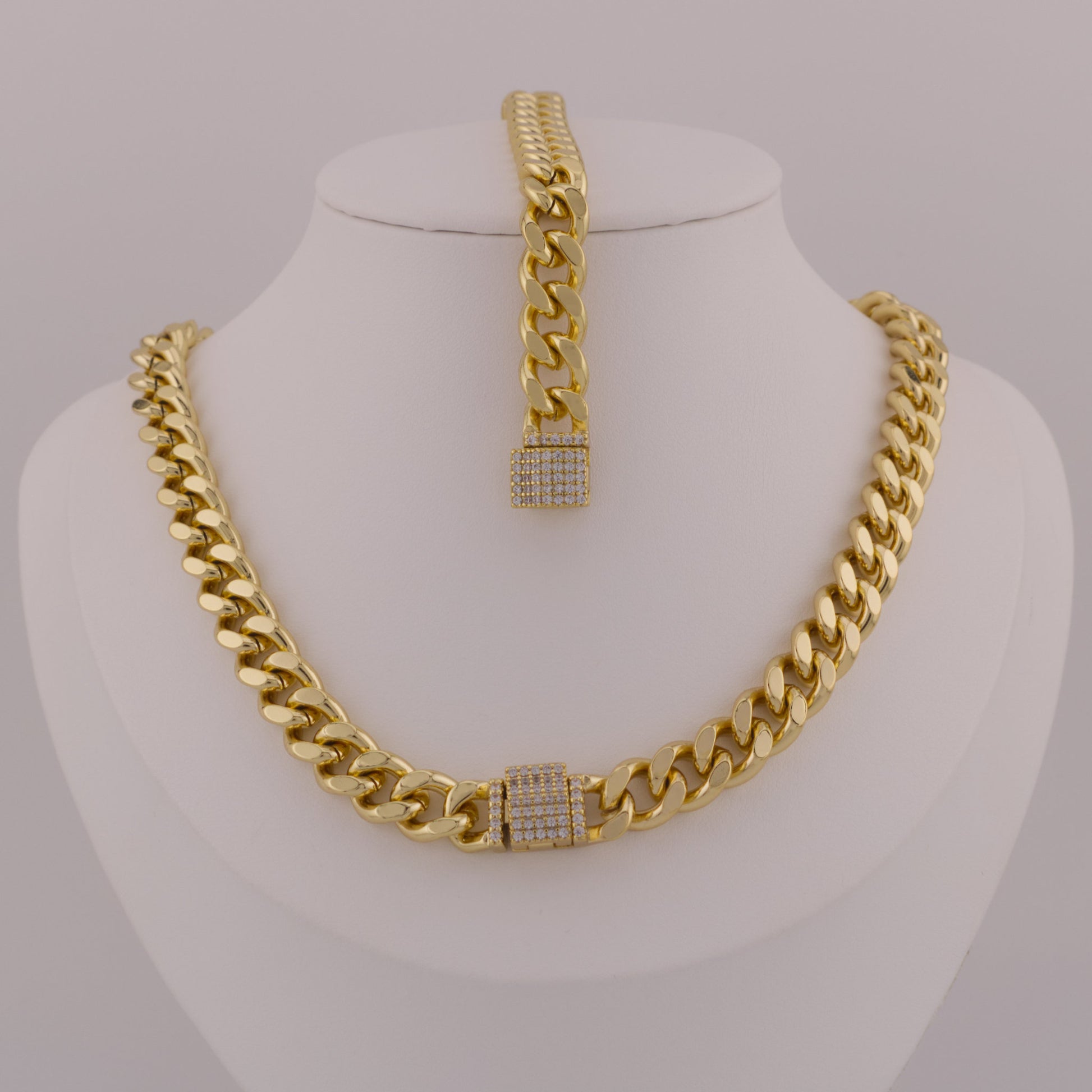 Gold chain necklace and bracelet set on a mannequin bust against a gray background