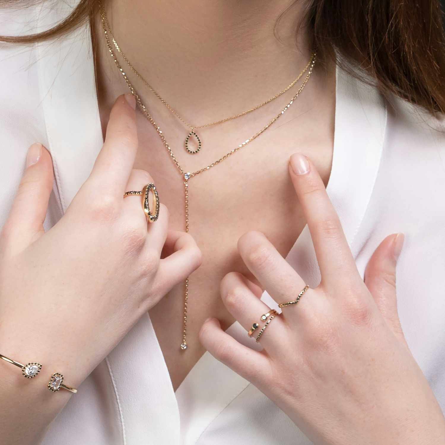 Close-up of a person wearing multiple gold necklaces and rings on a white background