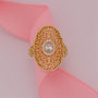 Gold ring with intricate design on a pink ribbon
