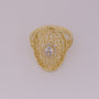 Gold ring with intricate design and central gemstone on a light gray background