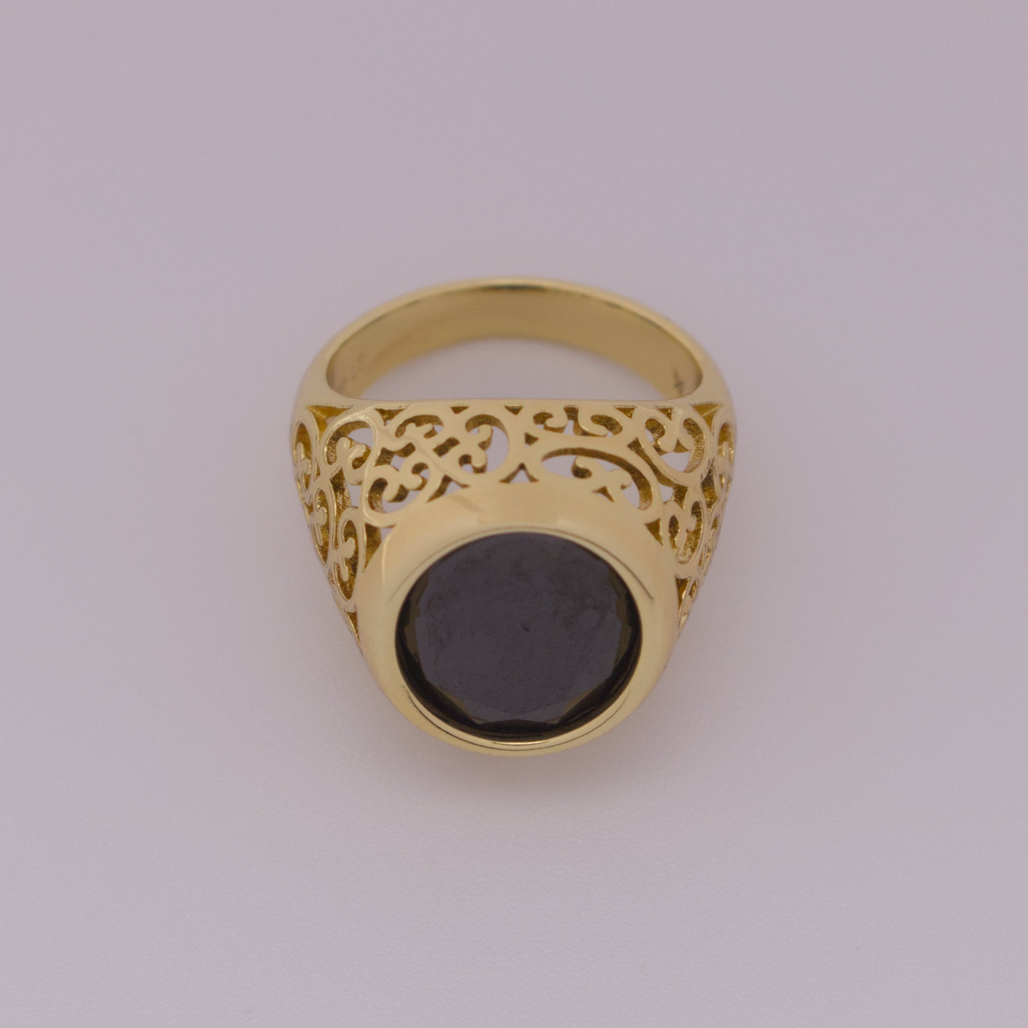 Gold ring with a black gemstone on a light gray background