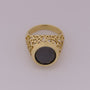 Gold ring with a black gemstone on a light gray background