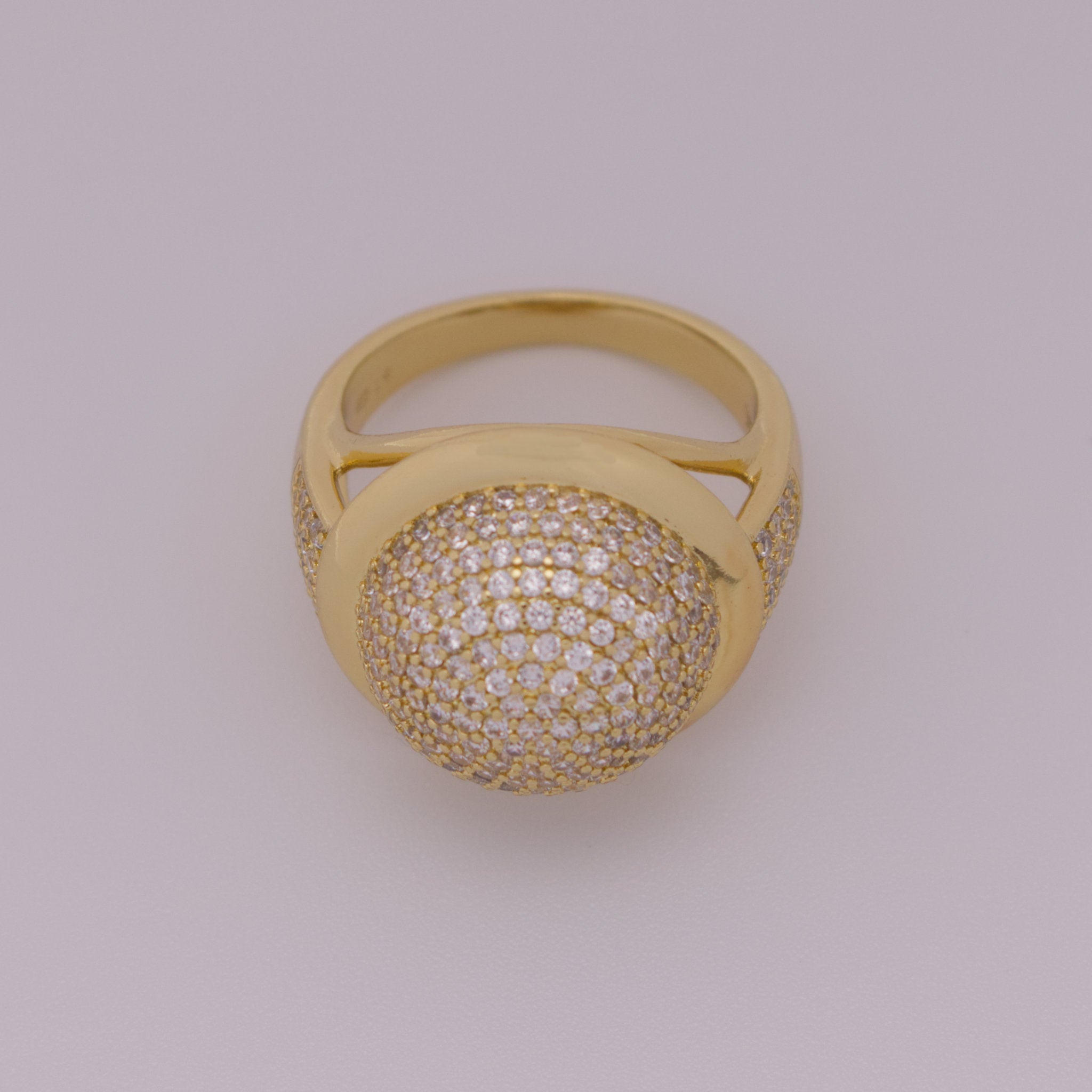 Gold ring with diamond-studded ball on a light gray background
