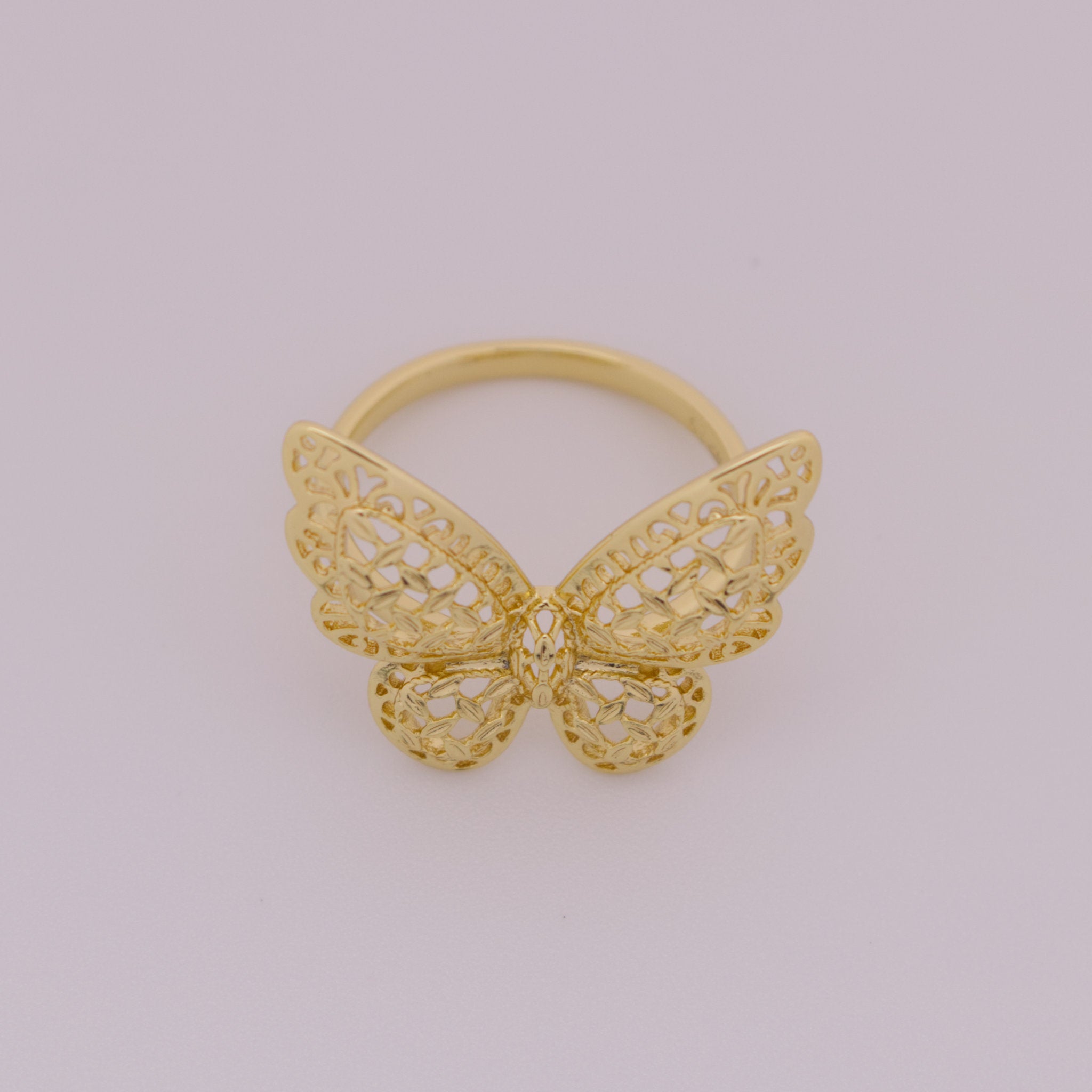 Gold butterfly ring on a light gray background