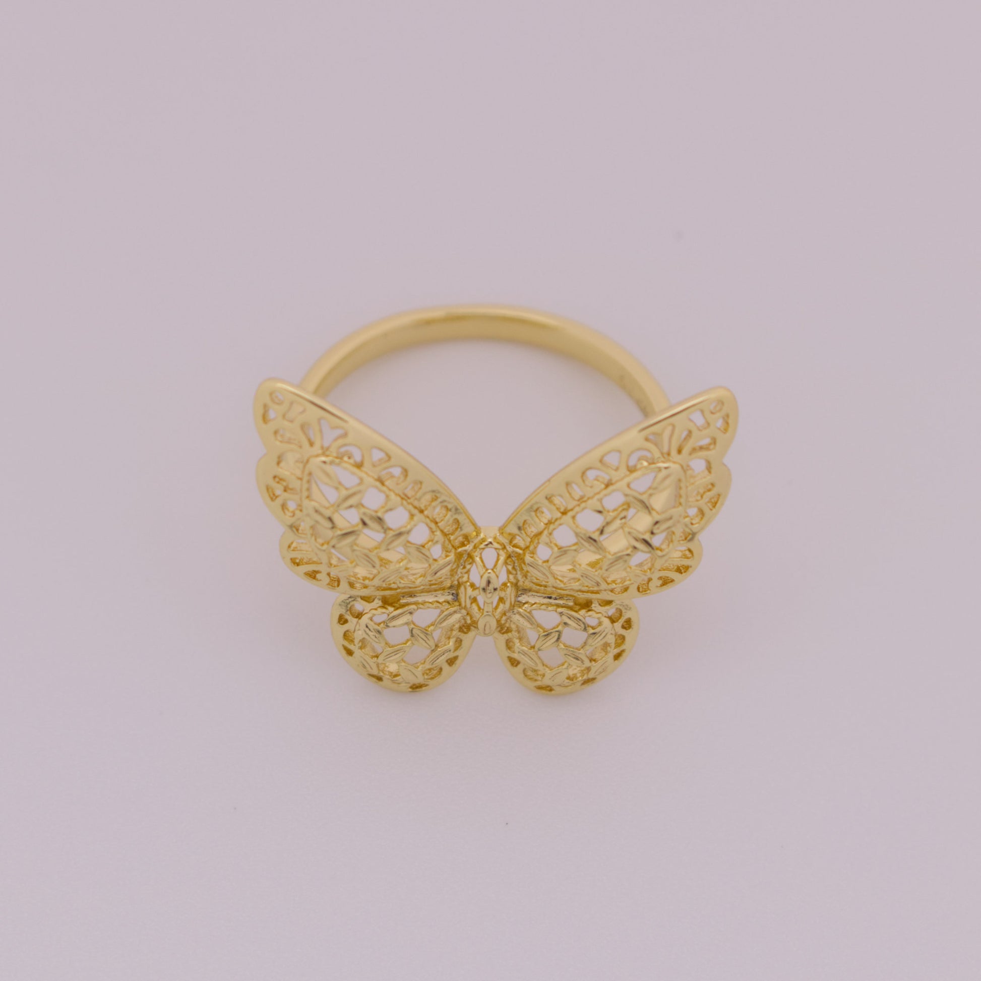 Gold butterfly ring on a light gray background