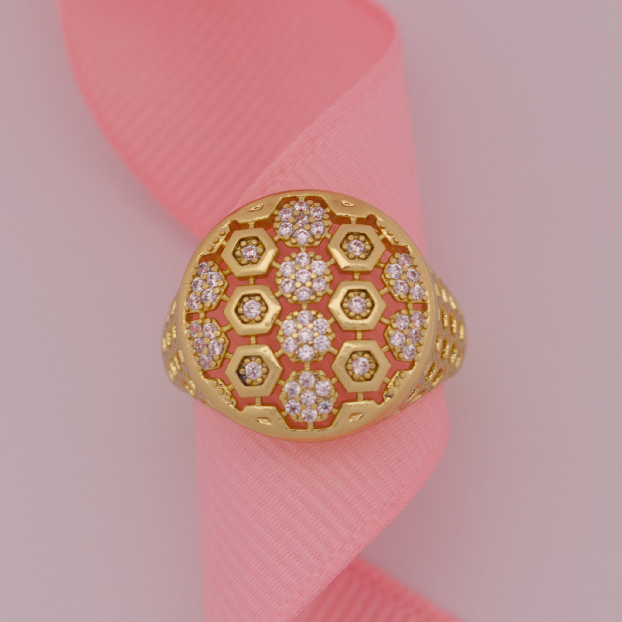 Gold ring with hexagonal pattern on a pink ribbon
