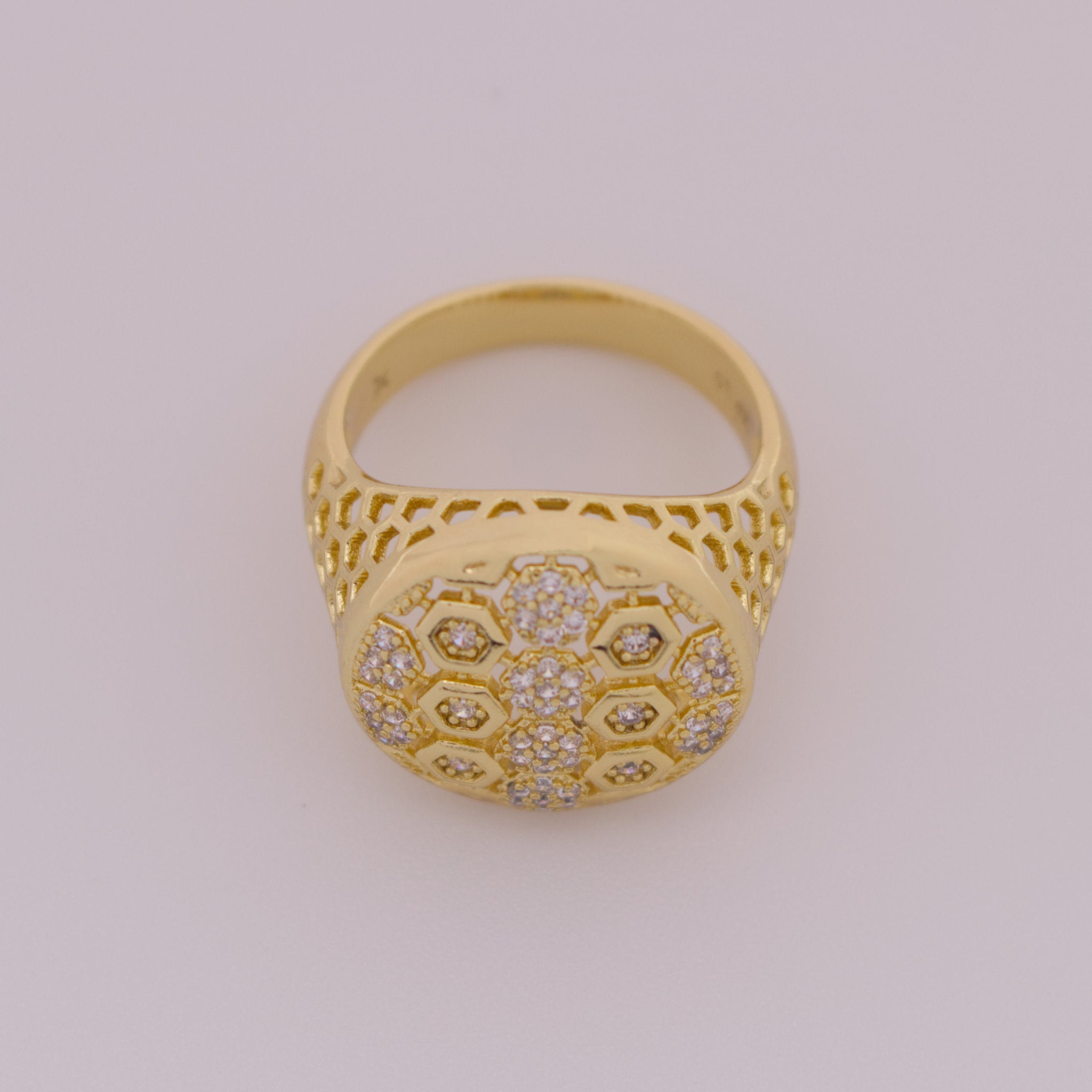 Gold ring with intricate design on a light gray background