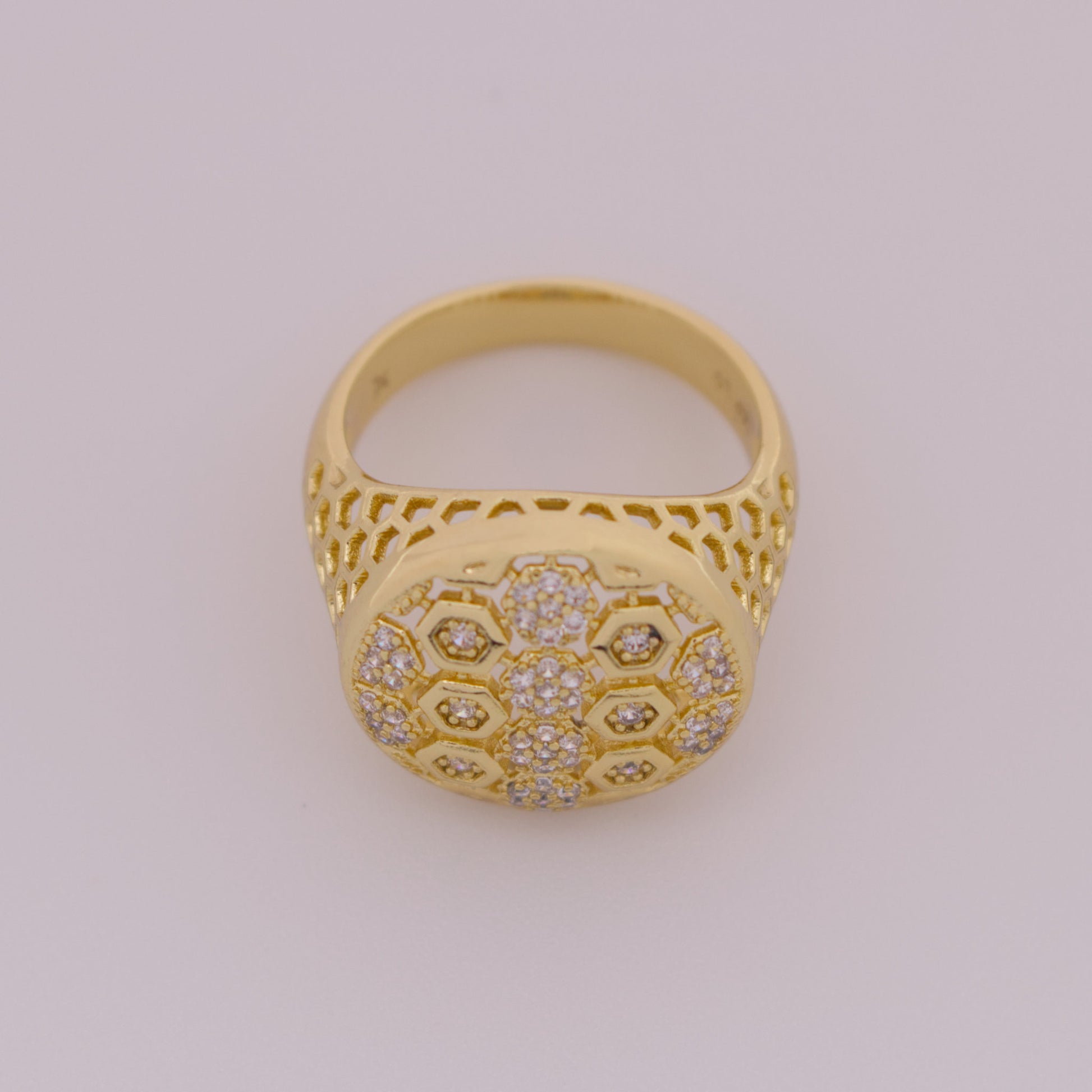 Gold ring with intricate design on a light gray background