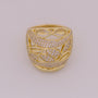 Gold ring with intricate design and diamond accents on a light gray background