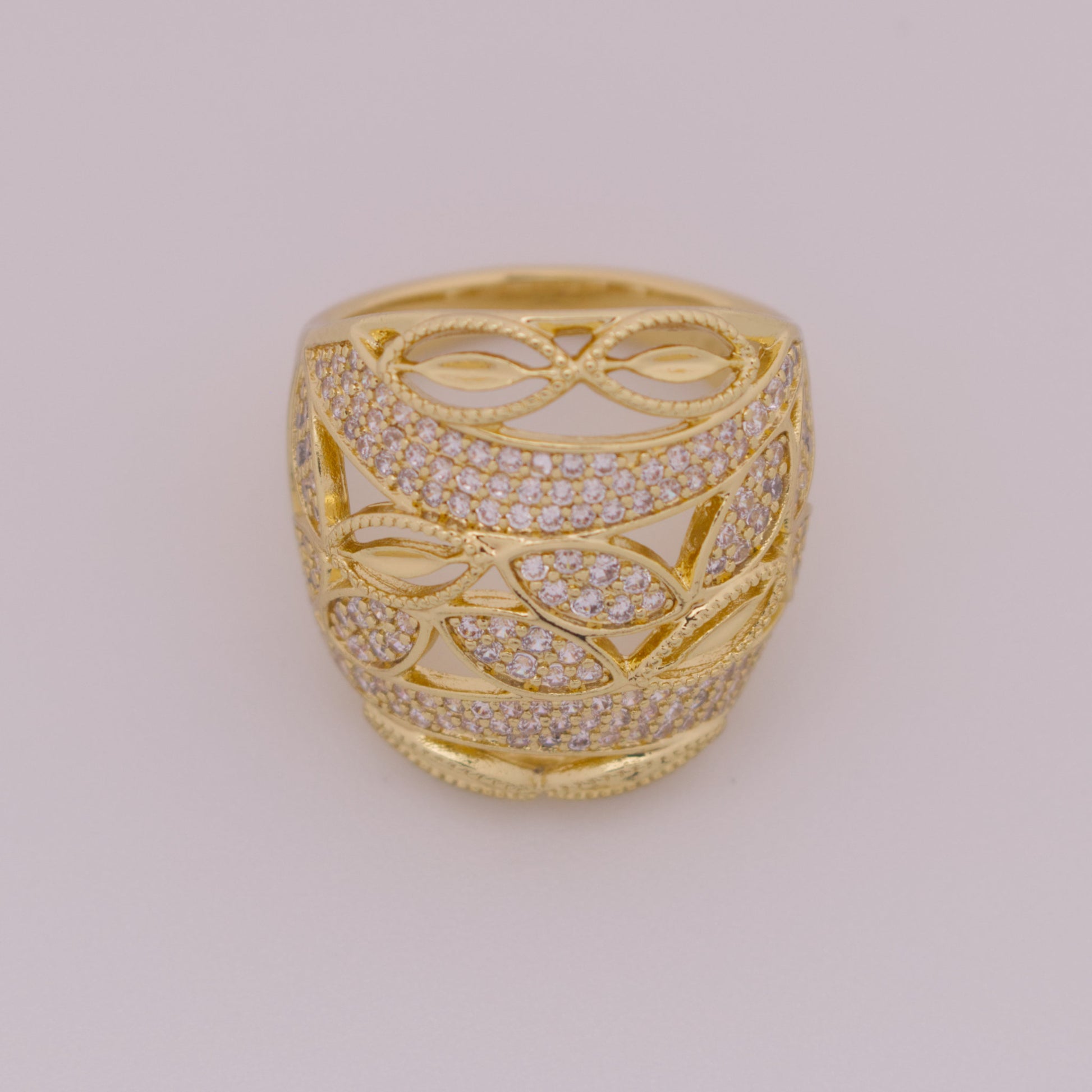 Gold ring with intricate design and diamond accents on a light gray background