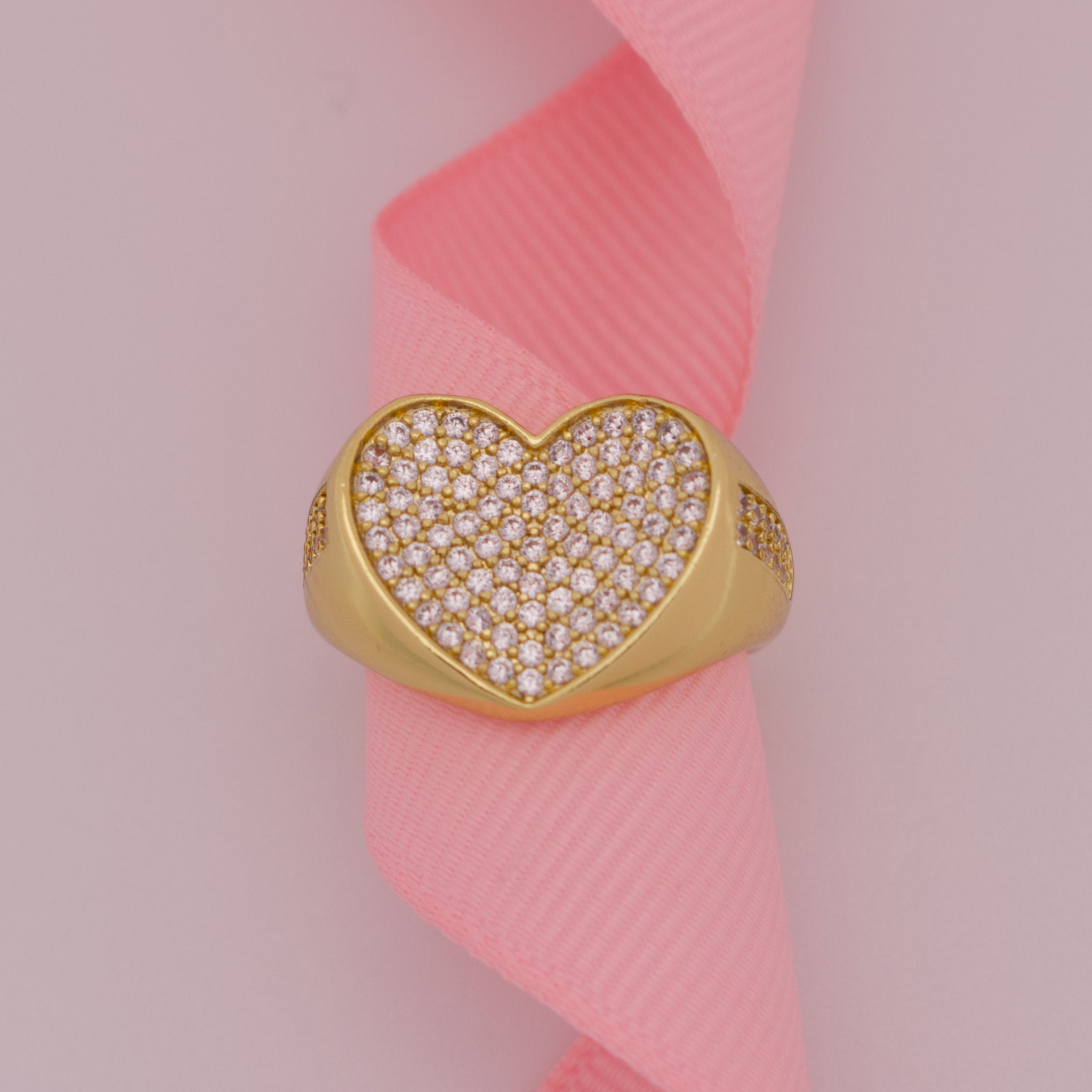 Gold heart-shaped ring with diamonds on a pink ribbon