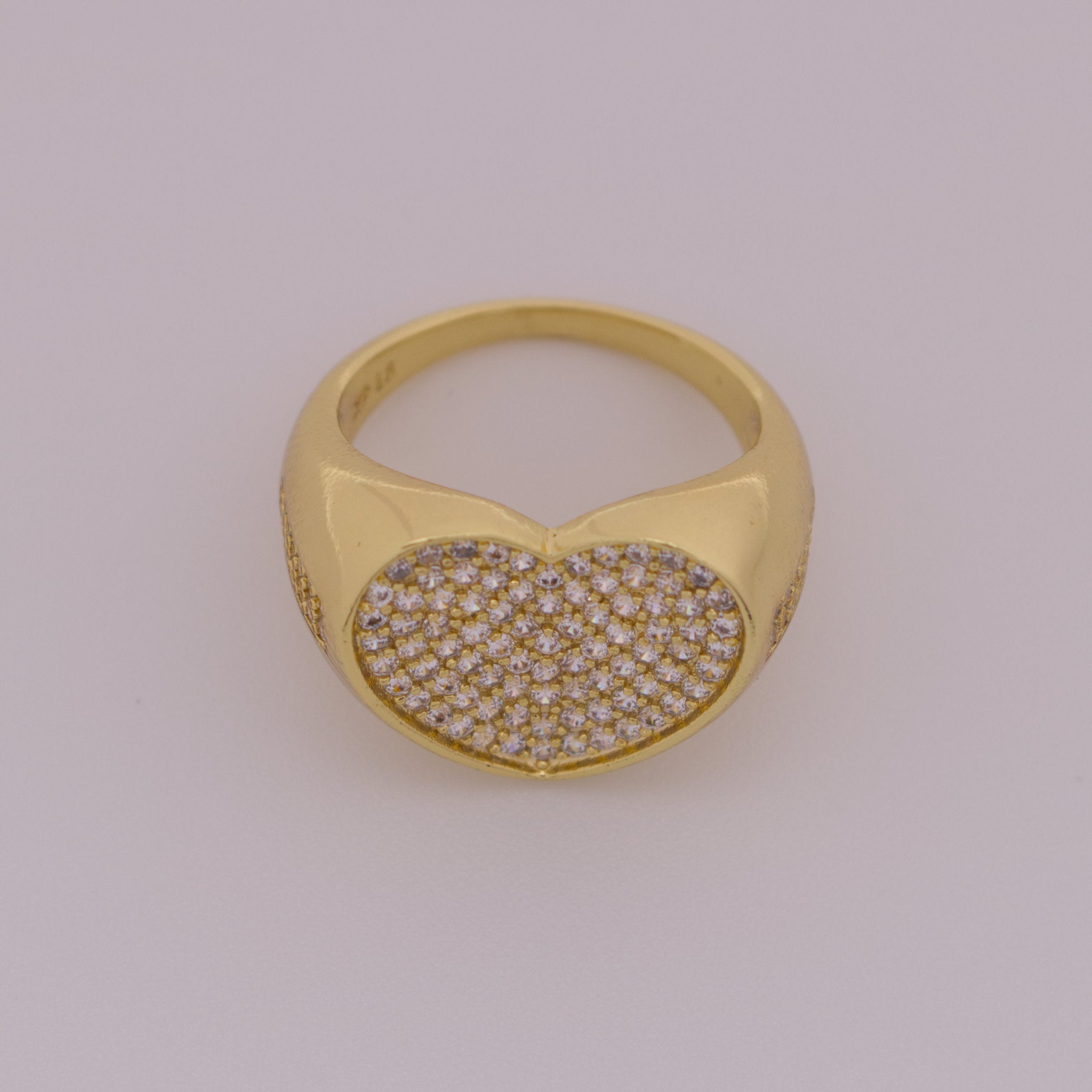 Gold ring with a heart-shaped diamond pavé setting on a light gray background