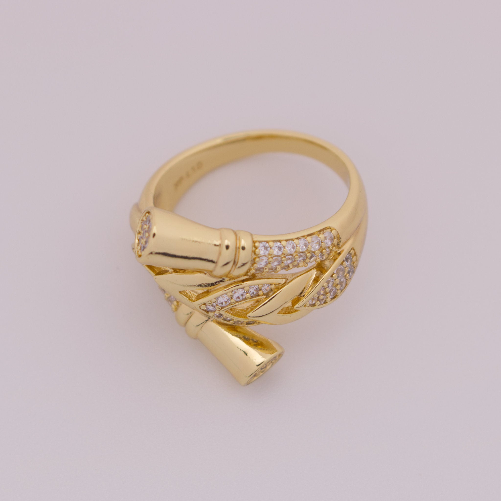 Gold ring with leaf design on a light gray background