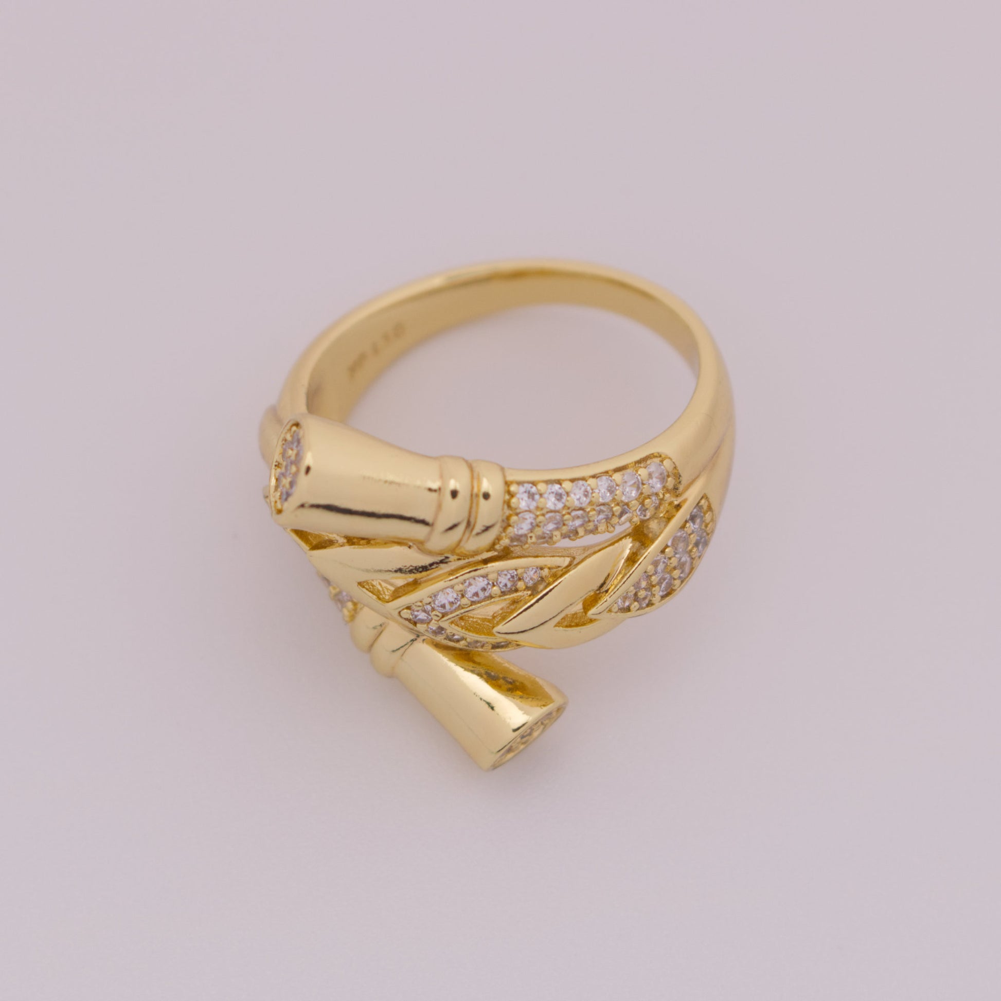 Gold ring with leaf design on a light gray background
