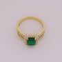 Gold ring with a green gemstone on a light gray background