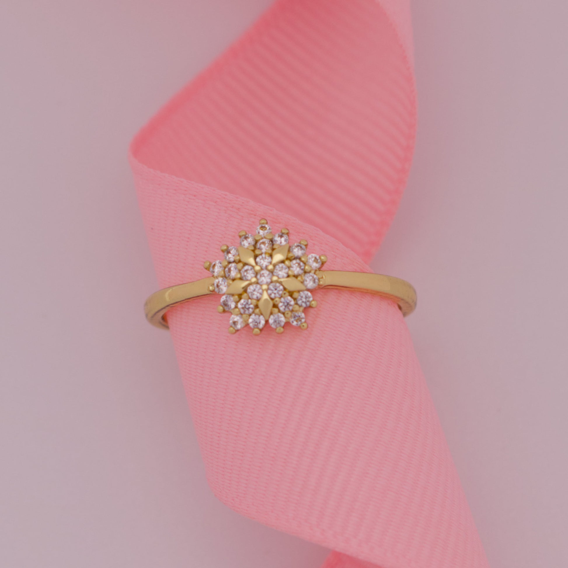 Gold ring with a diamond-like center on a pink ribbon