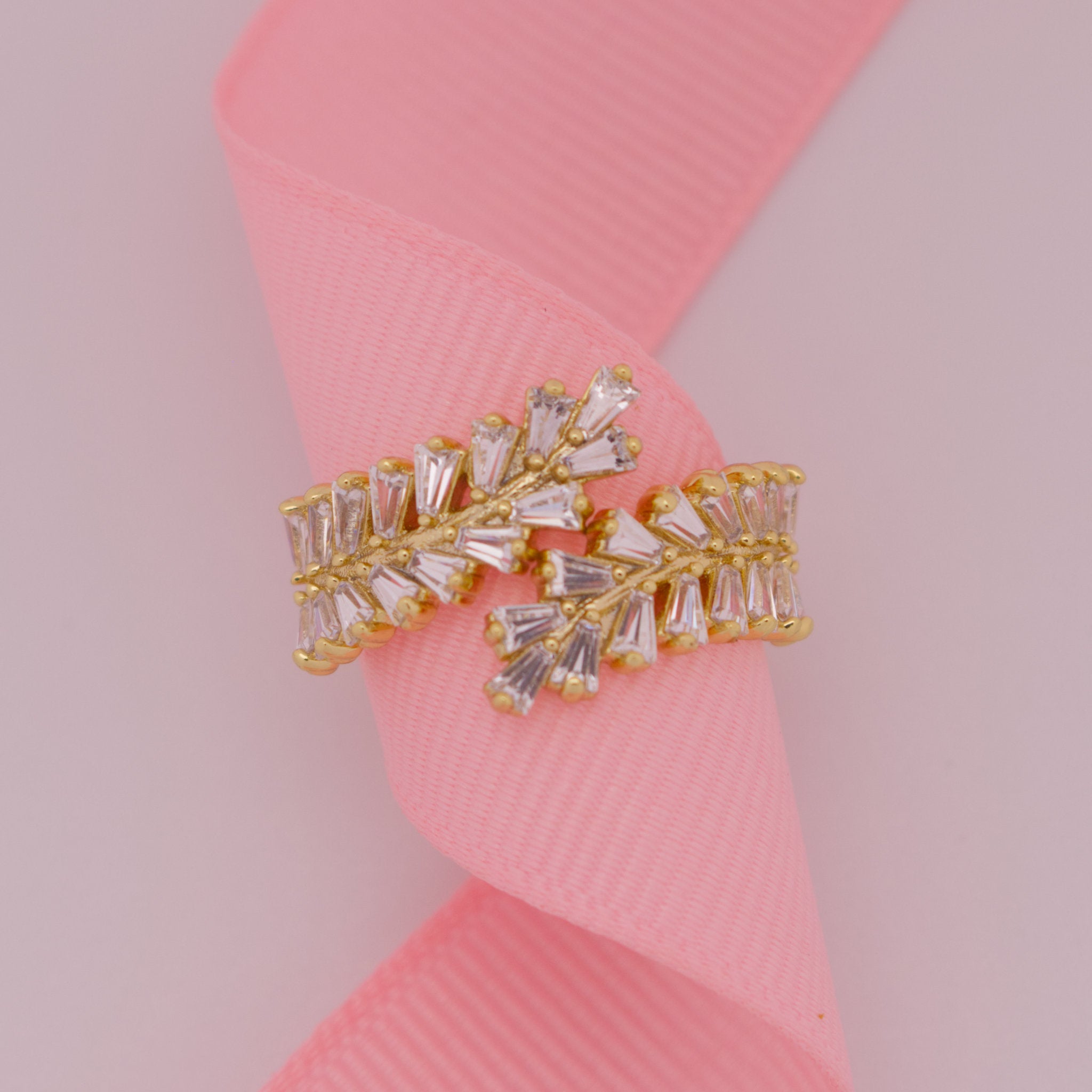 Gold and crystal earring on a pink ribbon