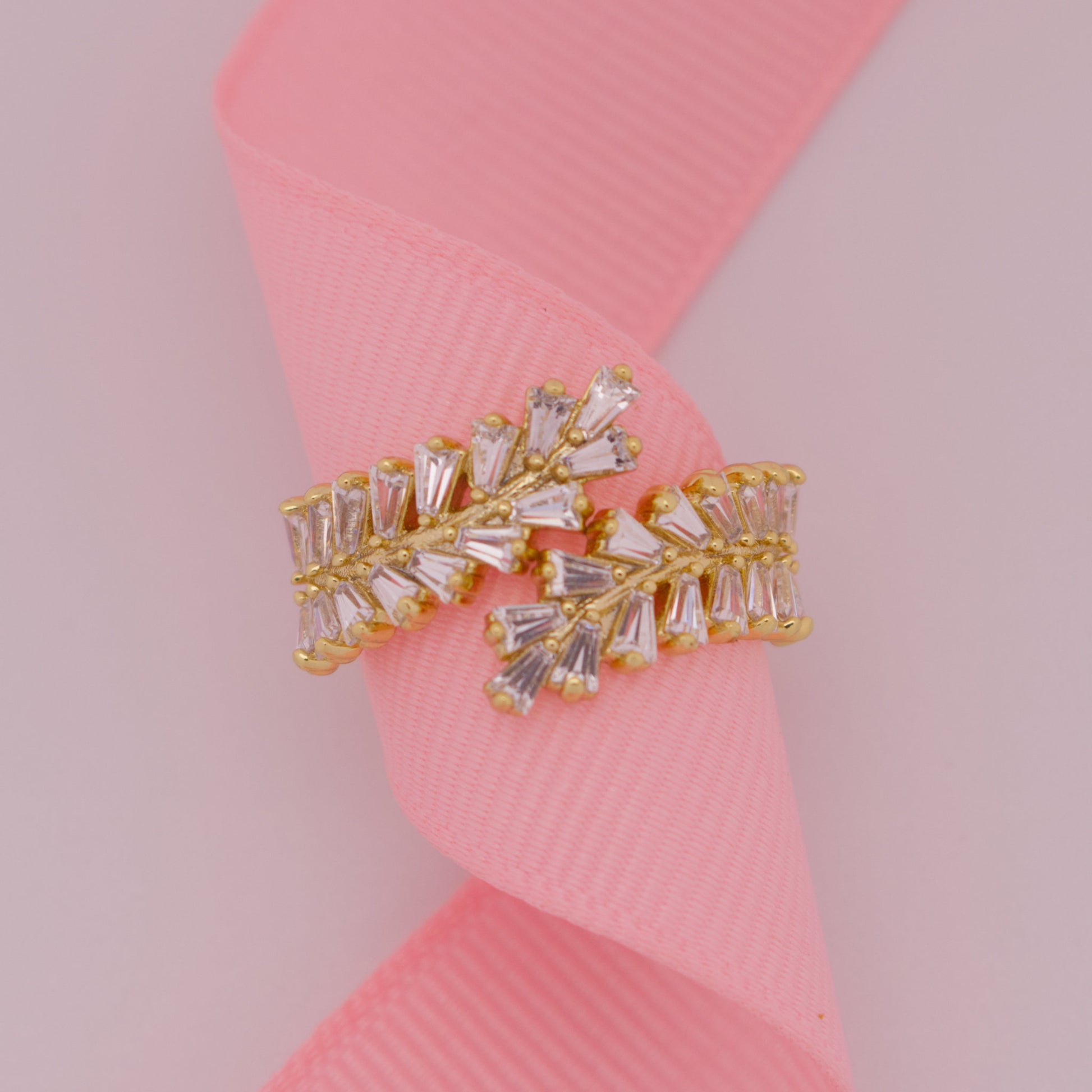 Gold and crystal earring on a pink ribbon