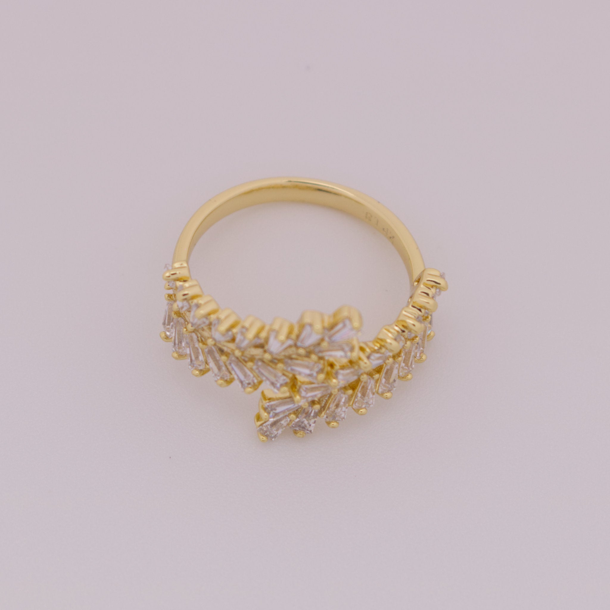 Gold ring with intricate design on a light gray background