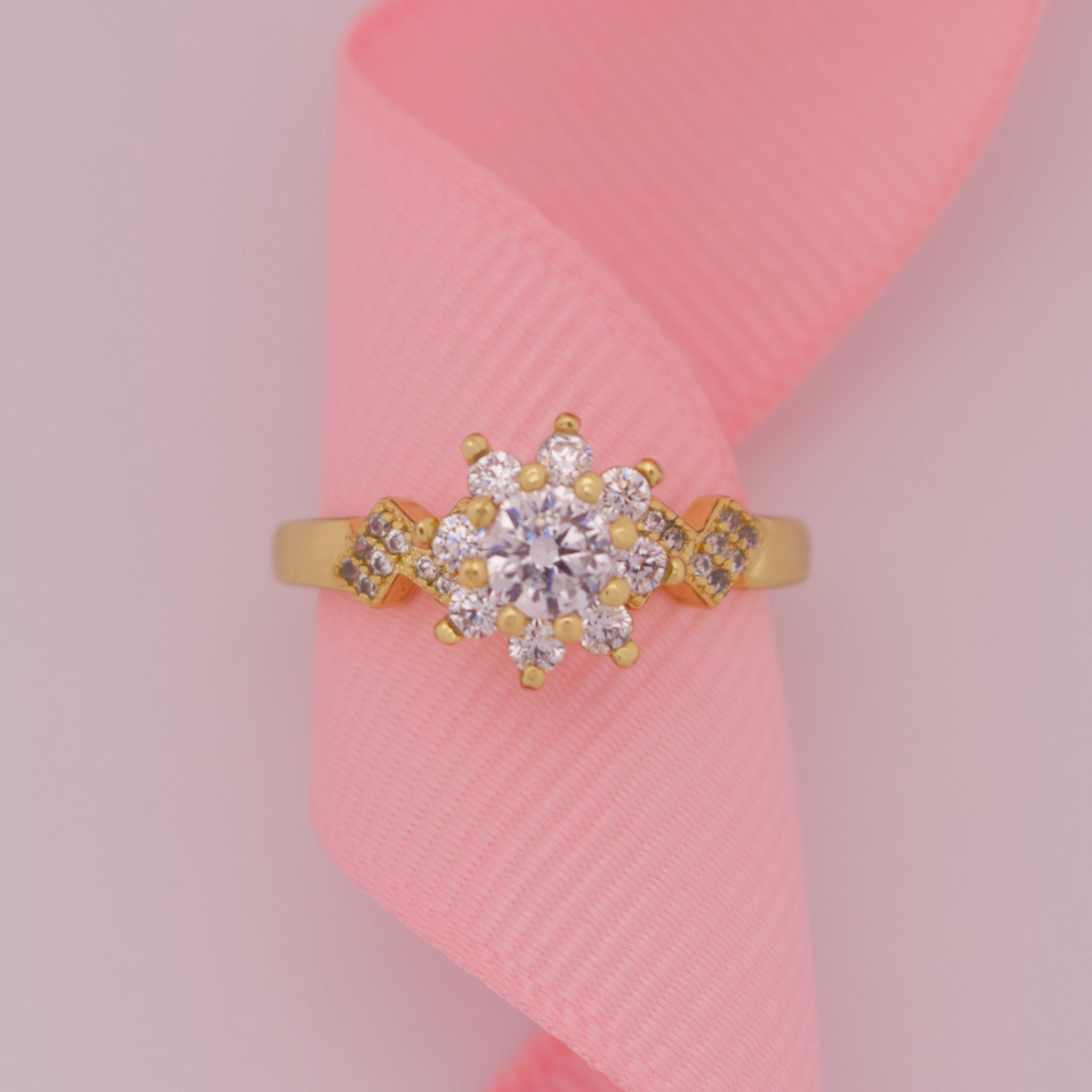 Gold ring with a diamond on a pink fabric background