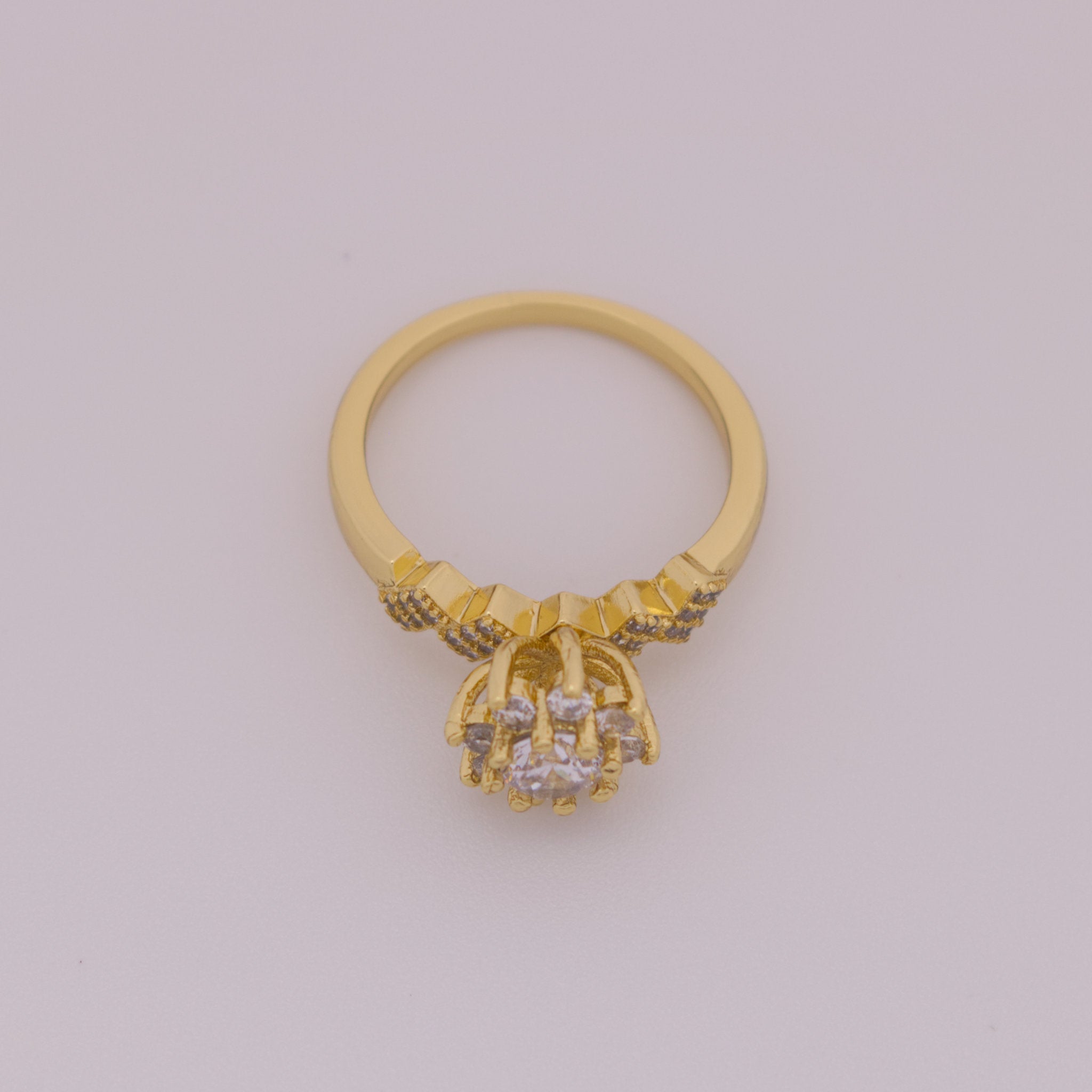 Gold ring with diamond-like stones on a light gray background