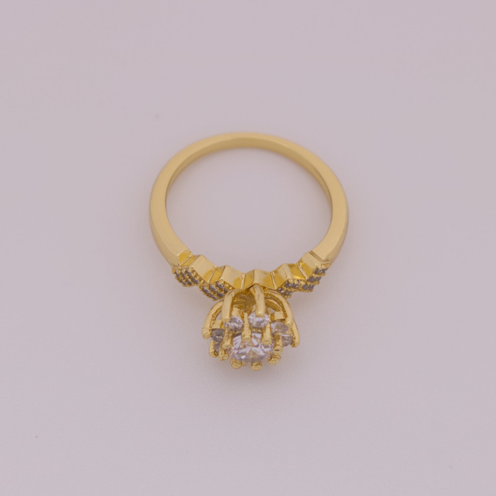 Gold ring with diamond-like stones on a light gray background
